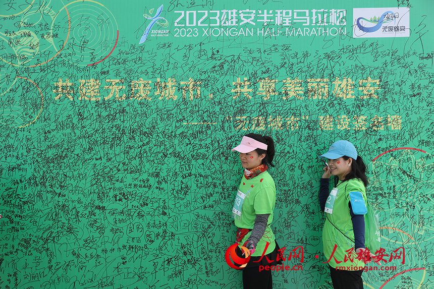 2023雄安半程馬拉松活動(dòng)現(xiàn)場(chǎng)，雄安新區(qū)生態(tài)環(huán)境局宣傳、倡導(dǎo)無(wú)廢城市展板吸引參賽選手一一簽名。人民網(wǎng) 李兆民攝
