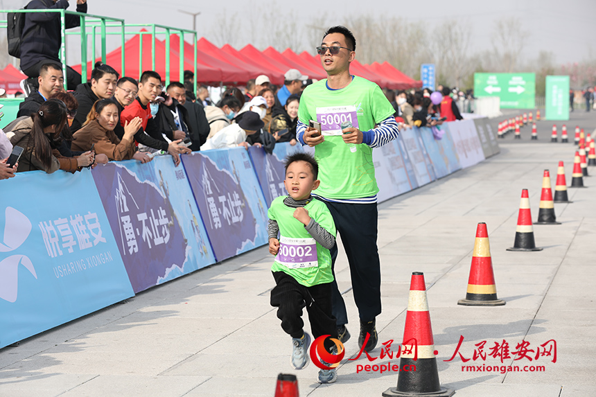2023雄安半程馬拉松現(xiàn)場，父親帶著兒子參加家庭夢想跑。人民網(wǎng) 李兆民攝
