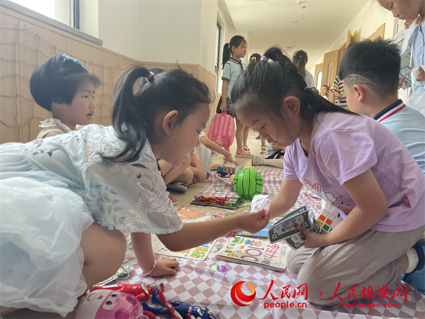 圖為“集市行樂”活動(dòng)中，學(xué)生用“悅?cè)輲拧边M(jìn)行交易。雄安容和悅?cè)萦變簣@供圖