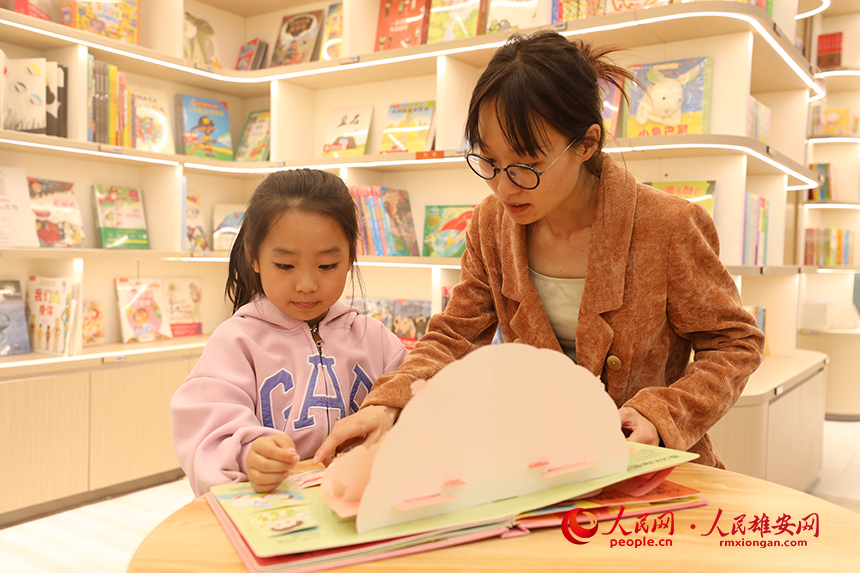 4月22日，在雄安新區(qū)新建片區(qū)的書店里，一名家長正在陪孩子閱讀。人民網記者 李兆民攝